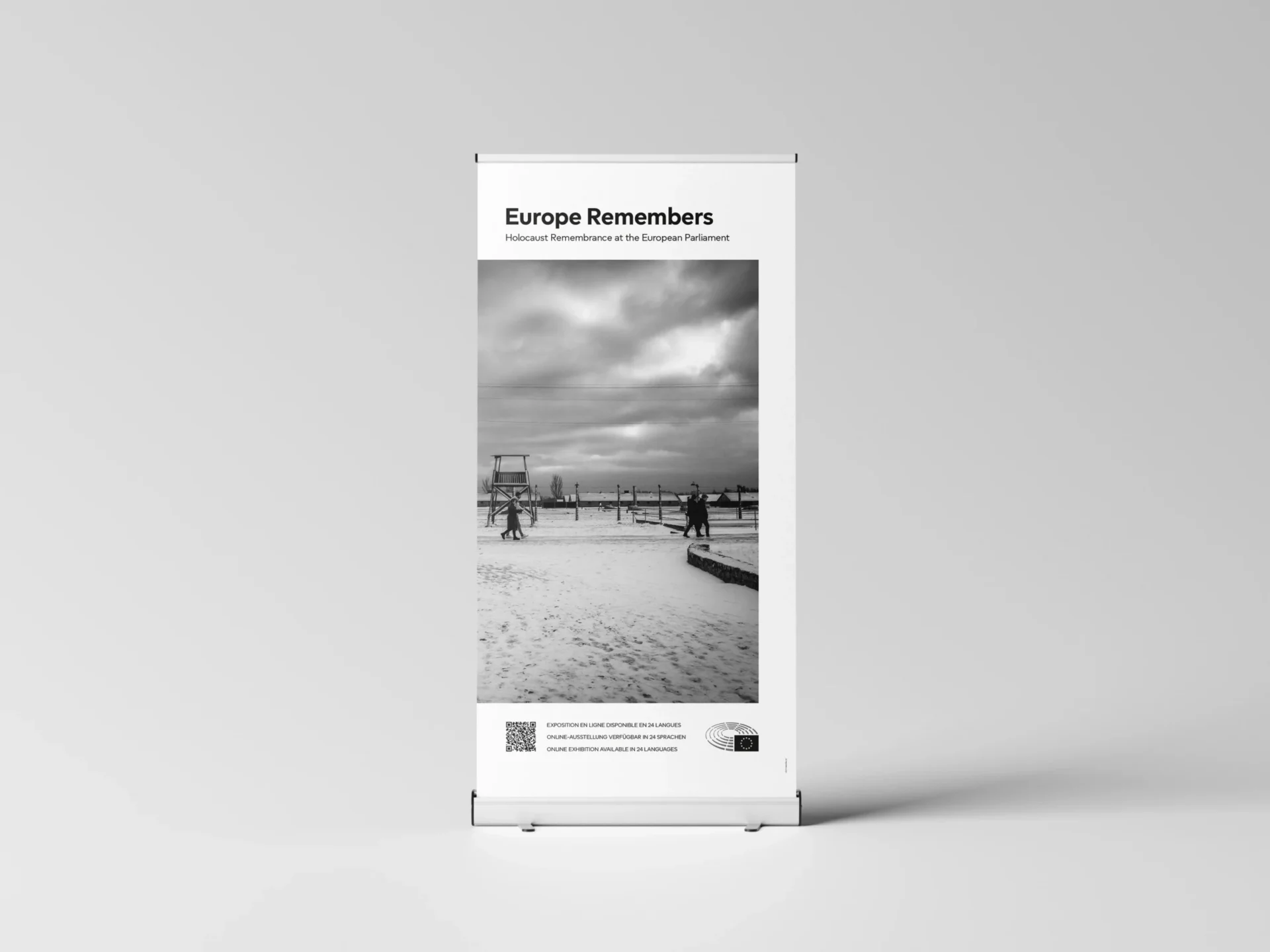 A standing roll-up banner based on the front page of the booklet, with the title ‘Europe Remembers: Holocaust Remembrance at the European Parliament’ at the top, a photograph displaying Auschwitz-Birkenau underneath, and at the bottom, a qr code along with the logo of the European Parliament.