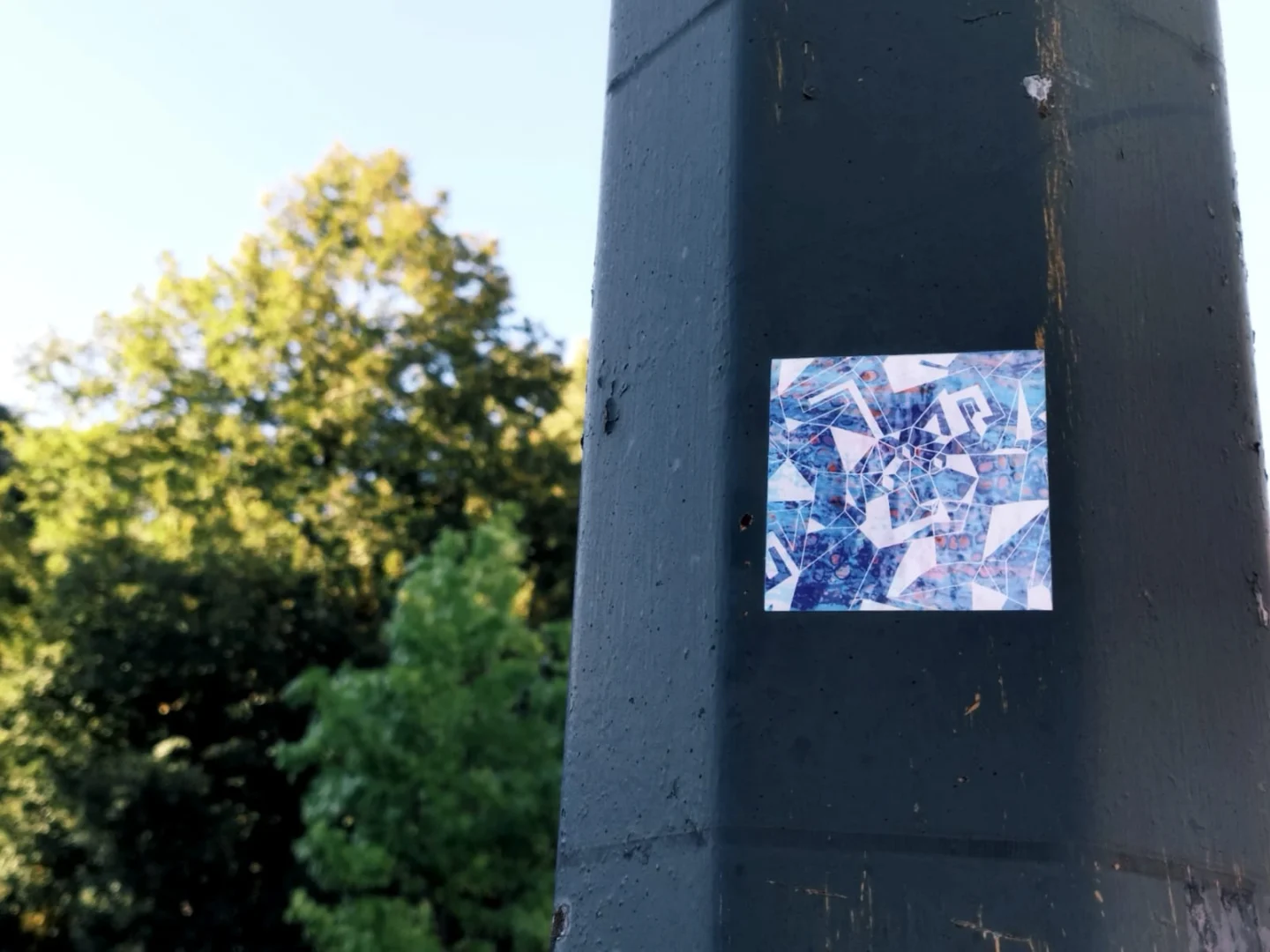 A sticker with graphics from the 'Miaou Expo' poster illustration placed on a street lamp.